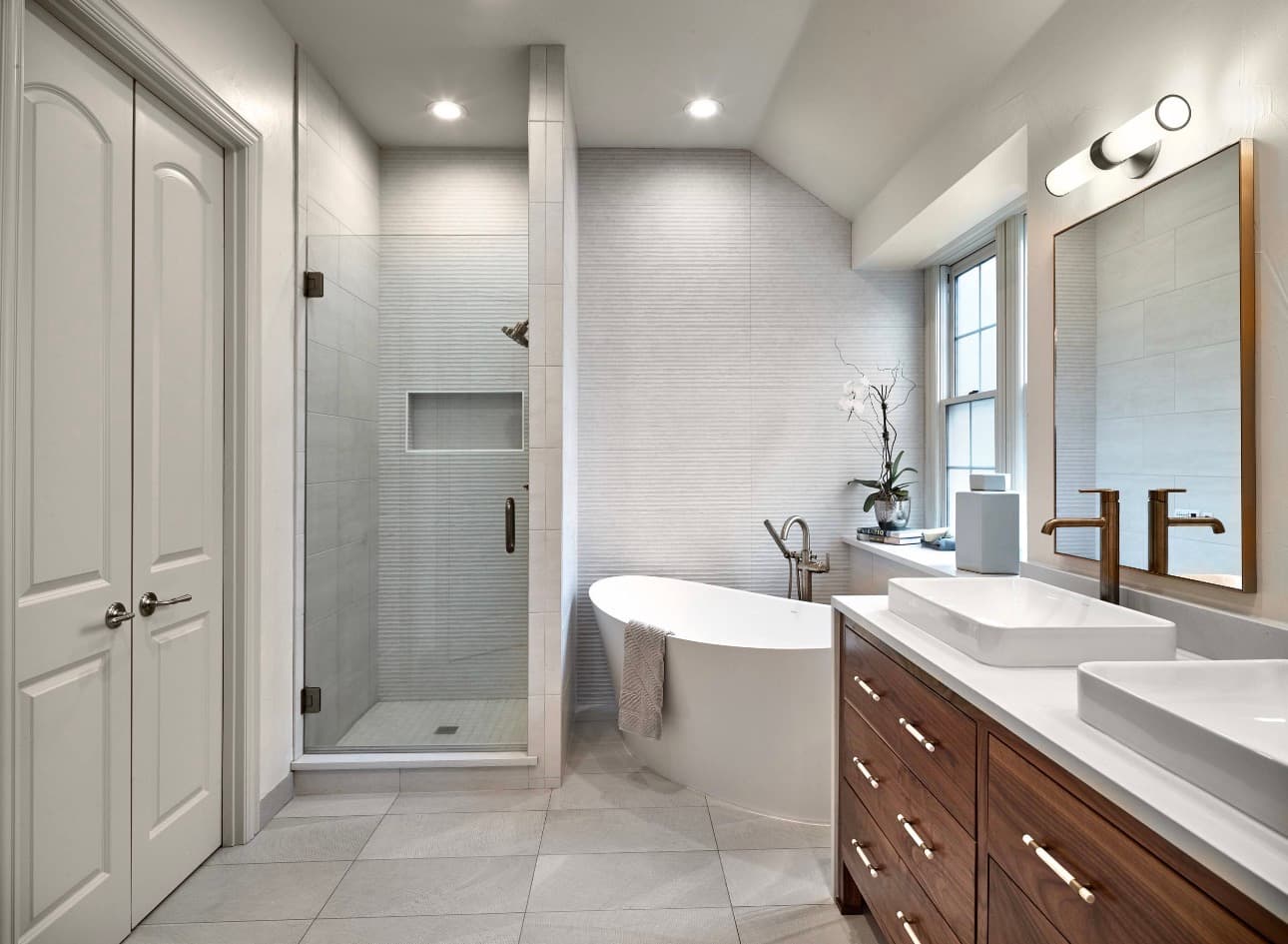 Master bathroom with freestanding oval tub, walk-in shower, and walnut vanity with vessel sinks